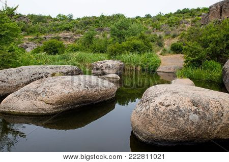 River in Aktovsky canyon, Ukraine. Big rocks in river, calm water. Green trees on the river bank. Wild nature landscape, spring time.