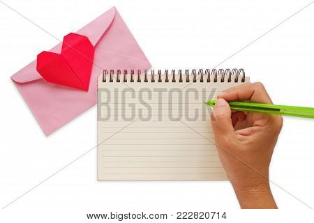 Hand writing on blank notebook with pink envelope and red heart paper origami on white background for Valentine's day and love concept