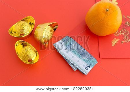 Chinese New Year Background 50 Ringgit Malaysia in Red Envelope with Mandarin Orange and gold ingots with Chinese Character Happiness and Prosperity on red background