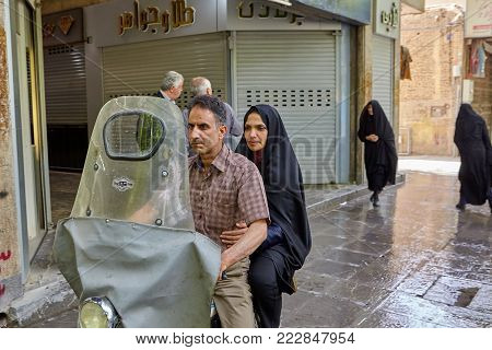 Isfahan, Iran - April 24, 2017: The husband and his wife go by motorbike along the city street.