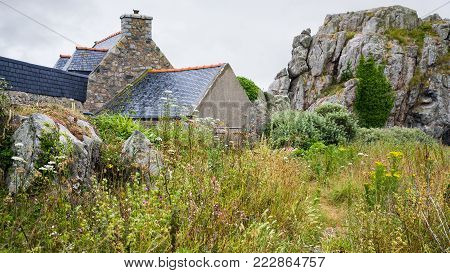 travel in France - traditional Breton stone house and rocks in Plougrescant town of the Cotes-d'Armor department in Brittany in rainy summer day