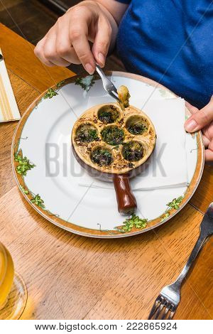 travel to France - woman eats snails in burgundy style (escargots a la bourguignonne) in restaurant in Etretat town in Normandy