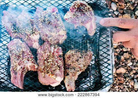travel to France - cooking fast food lamb meat in portable disposable grill on p beach Plage de la Baie de Launay in Ploubazlanec region of Brittany