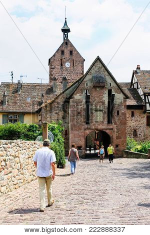 RIQUEWIHR, FRANCE - JULY 11, 2010: tourist walk to gate of Riquewihr city. Riquewihr is commune in Alsace Wine Route region, the town belongs to the association The most beautiful villages of France