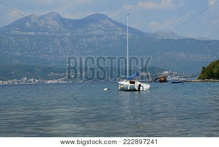 Sailing boat on a sea and an old half sunken ship wreck in distance