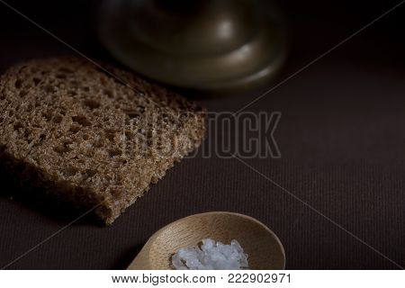 piece rough rye bread with coarse salt on a wooden background still life