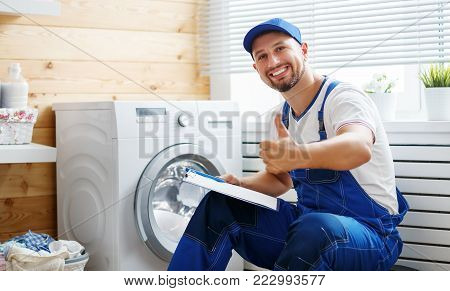 working man plumber repairs a washing machine in   laundry