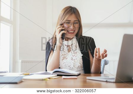 Young Office Woman Talking On Mobile Phone. Young Startup Businesswoman Using Her Cell Phone And Tal