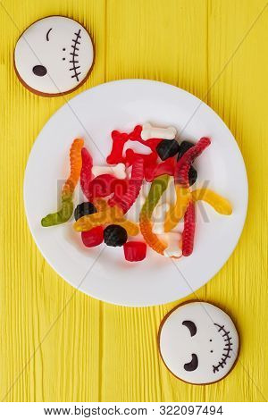 Halloween Background With Cookies And Candies. Plate With Colorful Jelly Sweets For Halloween On Yel