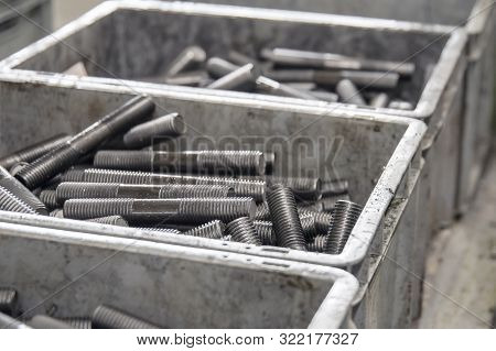 Large Number Of Metal Studs With Thread Randomly Lie In A Plastic Box, Close-up