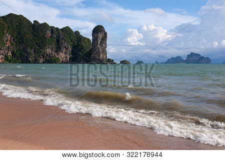 Picturesque beach with a view on the huge rock formation, sea view of Andaman sea and golden sand, iconic sight in Krabi province, Thailand.