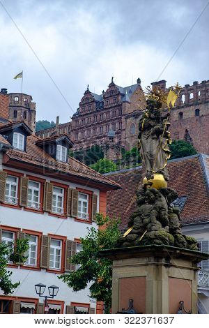 Heidelberg, Germany - August 7, 2019: The Madonna Statue In Kornmarkt Square With Heidelberg Castle 