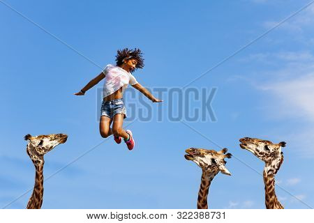 Beautiful Girl Jump Over Heads Of Cute Giraffes