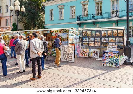 Moscow, Russia - September 13, 2019: Tourists On Arbat Street In Moscow Against Stand With Paintings