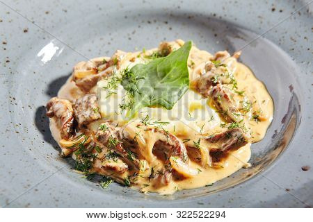 Classic Russian beef stroganoff or beef stroganov with mashed potatoes, mushrooms and greens close up. Restaurant main course with befstroganov in sour cream sauce or smetana, selective focus