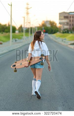 Dnipro / Ukraine - 06.02.2018: Beautiful Sexy Young Girl In Short Shorts Walking With Longboard In S