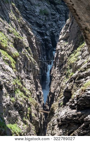 View Of A Wild River In The Viamala Gorge With Old Historic Stone Bridge In The Swiss Alps