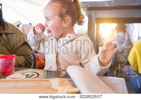Beautiful toddler child girl sitting on baby highchair  crying and screaming