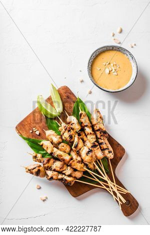 Chicken Grilled Satay Skewers Served With Lime And Peanut Sauce On White, Copy Space. Asian Thai Sty