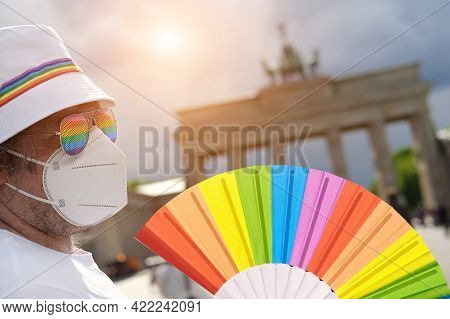 Mature Caucasian Lgbt Man In Berlin With Rainbow Fan And Ribbon On White Summer Hat. Rainbow, Symbol