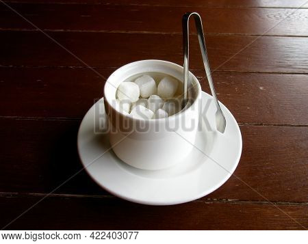 Refined Sugar In A White Sugar Bowl On A Wooden Table. Sugar Tongs.