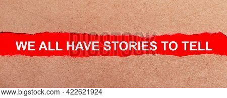 A Strip Of Red Paper Under The Torn Brown Paper. White Lettering On Red Paper We All Have Stories To