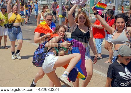 Gay And Lesbians Walking In The Gay Pride Parade. Parade Of Tolerance. Rainbow Flags At Gay Pride Pa