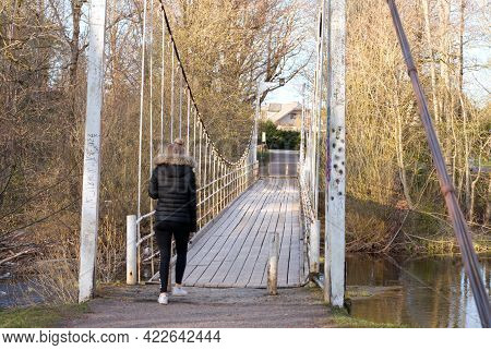 Old Hanging Footbridge Across A Small River In Estonia At Spring