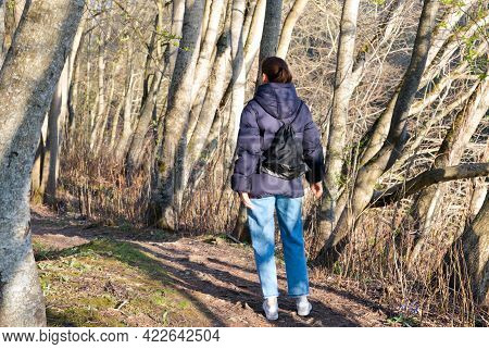 Young Woman With Backpack Walking In The Forest On Sunny Day