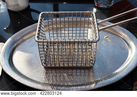 Empty Metallic Deep Fryer On A Table With Some Little Fries Pieces