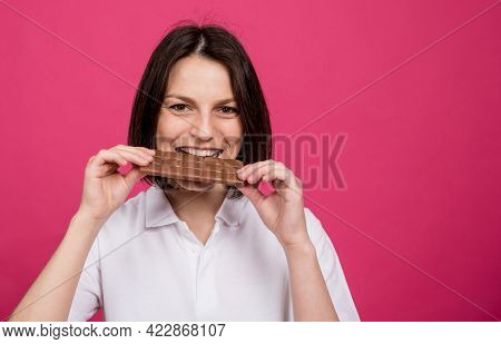 Beautiful Young Woman Bites A Bar Of Chocolate.