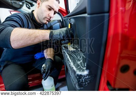 Car Service Worker Cleans Interiror With Special Brush