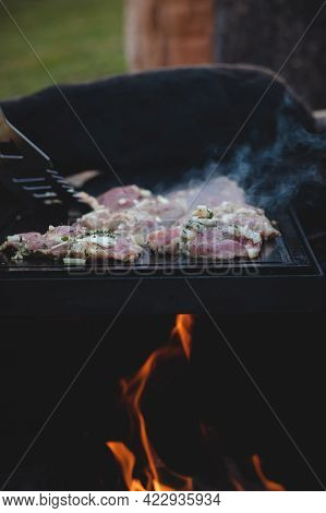 Man Uses A Steel Ladle To Turn A Loaded Pork Neck With Basil, Salt, Pepper And Oil From One Seared S