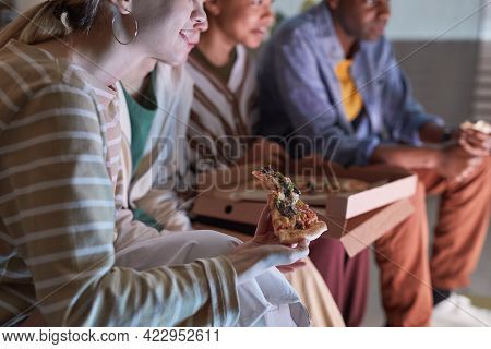 Close Up Of Young Woman Eating Pizza While Watching Tv With Friends At Home Lit By Blue Light, Copy 