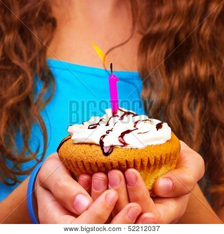 Birthday girl with festive cupcake in hands, make a wish, sweet holiday dessert, having fun on birthday party, happiness concept