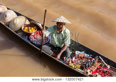 INLE LAKE MYANMAR - JANUARY 14 2016 : Unidentified Burmese man on small long wooden boat selling souvenirs trinkets and bijouterieat the floating market on Inle Lake Myanmar