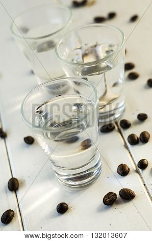 Sambuca in shot glasses and coffee beans on white background