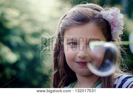 Portrait of cute lovely little girl blowing soap bubbles.