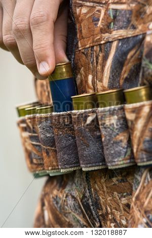 hand of hunter pulling cartridge from the bandoleer closeup