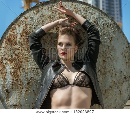 fashionable and sexy young brunette woman in black bra and leather jacket in the street