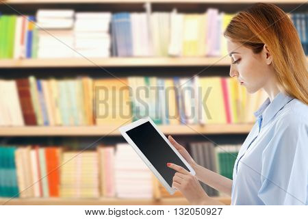 Young woman holding tablet-pc in library
