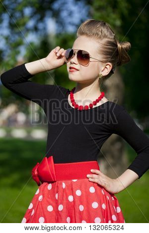 Pin-Up. Lovely little girl in the retro red dress in summer park