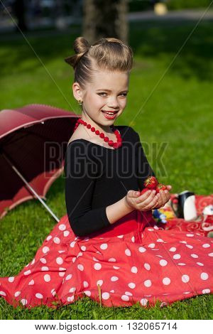 Pin-Up. Lovely little girl in the retro red dress in summer park