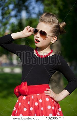Pin-Up. Lovely little girl in the retro red dress in summer park
