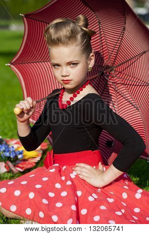 Pin-Up. Lovely little girl in the retro red dress in summer park