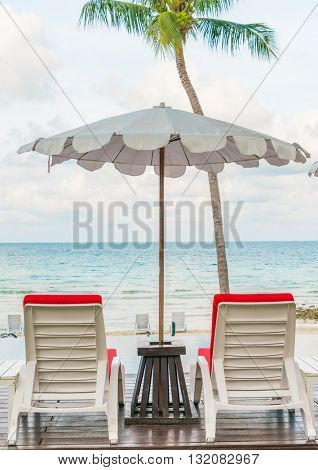 Beautiful beach chairs with umbrella around outdoor swimming pool neary sand and sea