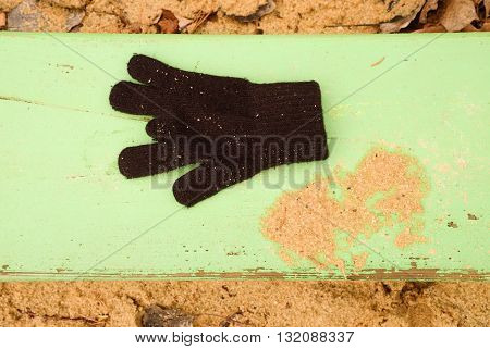 Lost Woolen Gloves On Green Bench. Sandy Gren Wooden Bench.  Sandbox With Dirty Sand In Kindergarden