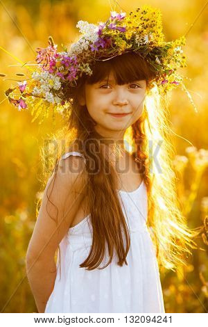 Happy cute girl wearing a wreath of wildflowers