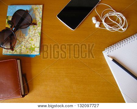 travel concept flay lay, sunglasses, map, headphones, phone, pencil, copybook