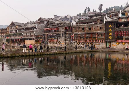 Hunan China 14 Nov 2011: Tourists Crossing Stone Bridge At Phoenix Ancient Town.